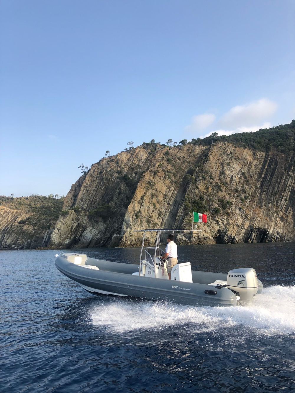 Gommone in navigazione lungo la costa rocciosa